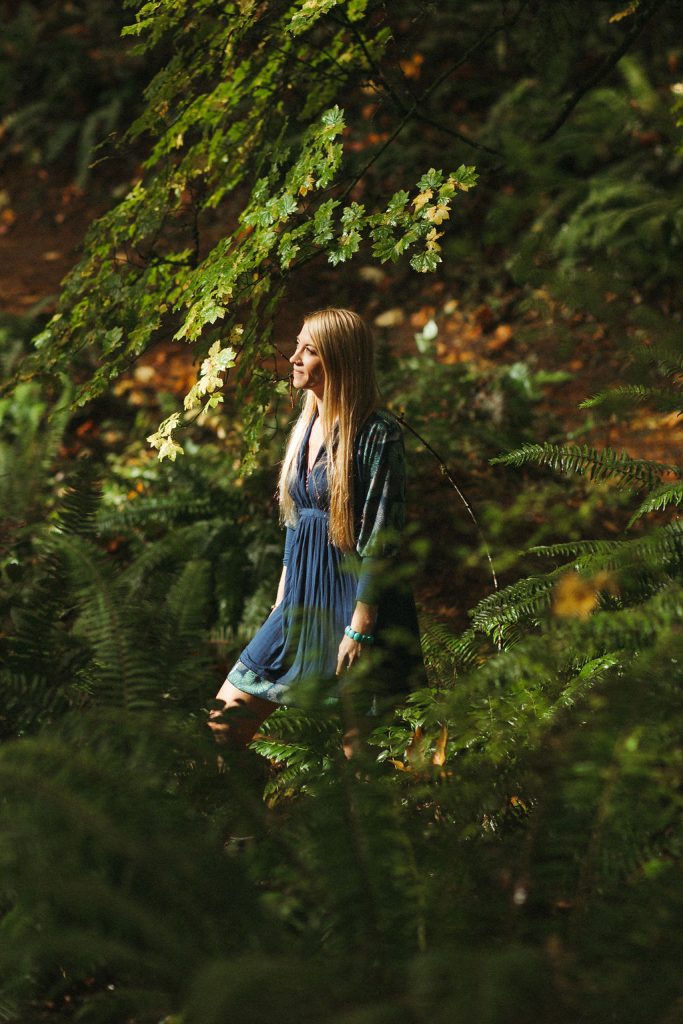 Lindsey Walker, owner of Mockingbird Remedies, walking in a dense green forest